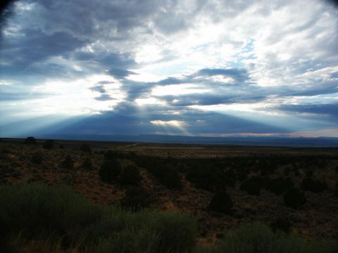 2001 Mercury Grand Marquis - Sunbeams pierce through a dramatic cloudscape, illuminating a wide, open expanse of dry terrain.