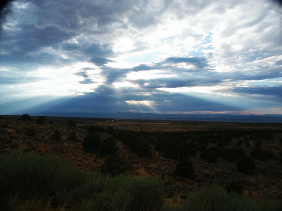 Sunbeams break through dramatic clouds over a vast, arid landscape