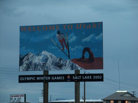 2001 Mercury Grand Marquis - A billboard advertises Utah as a destination, skiing and Delicate Arch, with a sign for the 2002 Winter Olympics.