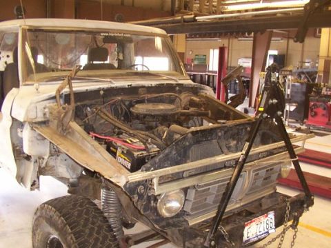 1978 Ford Bronco - This white pickup truck is undergoing repairs with its hood open, revealing the engine and front grille.