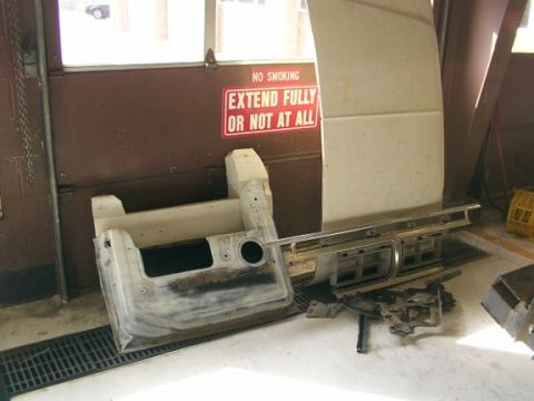 1978 Ford Bronco - Disassembled car parts, including a grille and door panel, are laid out on the floor of a garage.