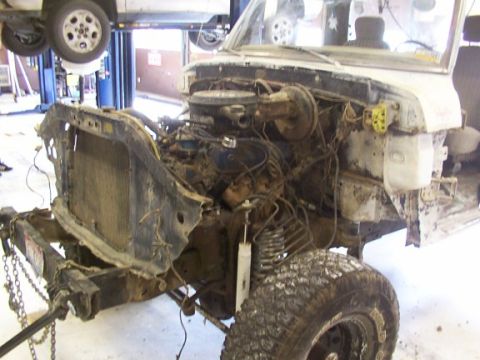 1978 Ford Bronco - Front end of a vehicle undergoing repair, with the engine and radiator removed, showing the chassis and suspension components.