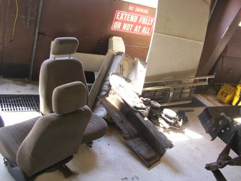 1978 Ford Bronco - Car seats and parts are stored in a garage. A sign is visible on the wall.