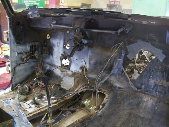 Disassembled vehicle interior with exposed wires and rusted metal