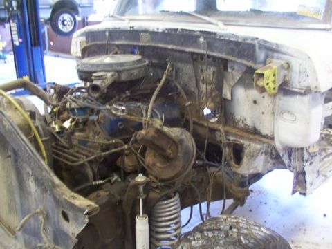 1978 Ford Bronco - The front end of a truck is disassembled, revealing the engine and suspension components. Another vehicle is on a lift in the background.