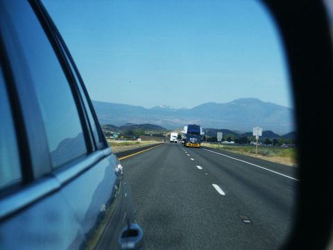2001 Mercury Grand Marquis - A view from a side mirror shows trucks on a highway with mountains in the background.