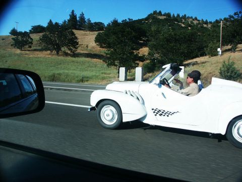 2001 Mercury Grand Marquis - A driver in a white convertible with a checkerboard decal cruises down a sunny highway.