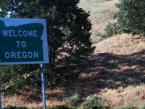 2001 Mercury Grand Marquis - A sign welcomes travelers to Oregon, with dry, grassy hills and trees in the background.