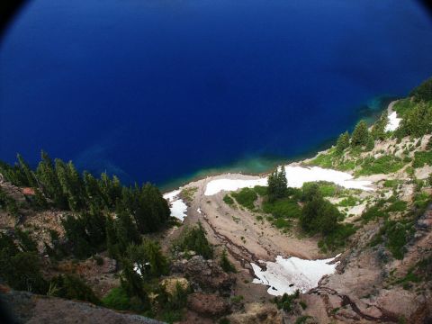 2001 Mercury Grand Marquis - A scenic view of a deep blue lake surrounded by a rocky, tree-covered cliff with snow patches.