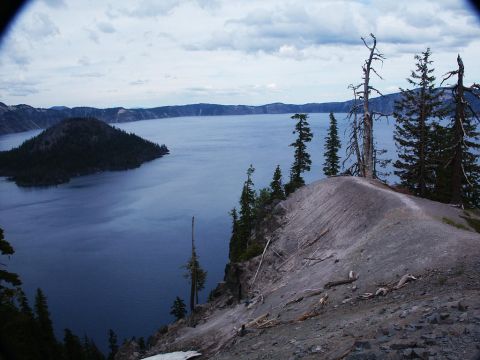 2001 Mercury Grand Marquis - A vast blue lake is surrounded by mountains and dotted with trees, under a cloudy sky.