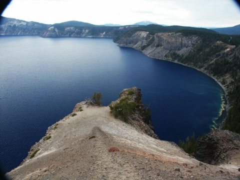 2001 Mercury Grand Marquis - A vast blue lake is surrounded by cliffs and dense forest under a cloudy sky.
