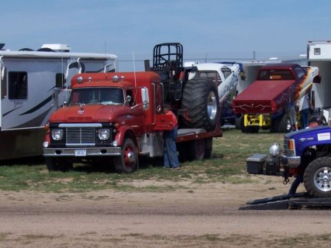 1972 Ford Ranchero - A 1972 Ford F-series truck is seen transporting a tractor, with other vehicles and RVs present at the scene.