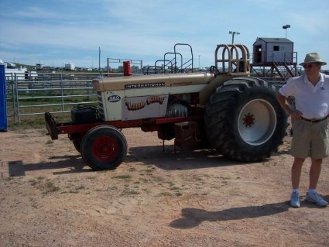 1972 Ford Ranchero - A man stands next to an International tractor with large rear wheels and "Little Gilly" painted on its side.