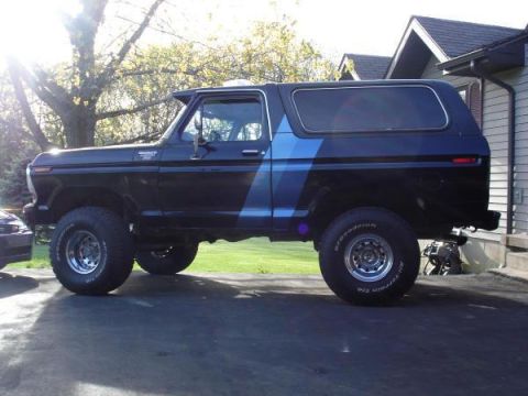 1979 Ford Bronco - Side view of a black 1979 Ford Bronco with blue racing stripes.