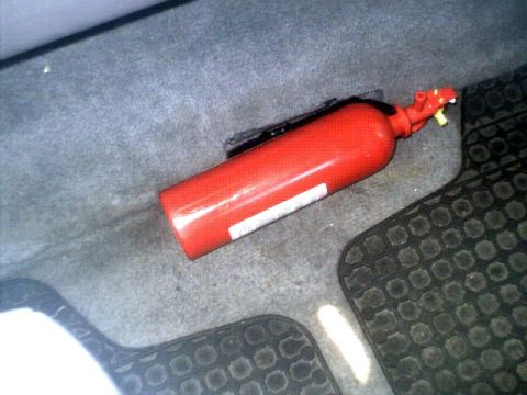 1996 Ford Bronco - A red fire extinguisher is visible on the floor of a vehicle, secured with a black bracket.