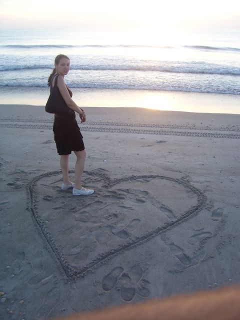 1994 Ford Probe - A woman poses on the sand next to a heart drawing as waves crash on the shore.