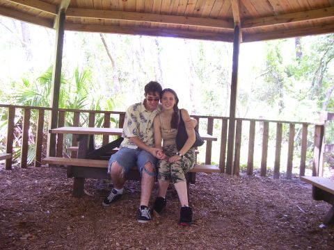 1994 Ford Probe - A couple sits together on a picnic bench within a wooden gazebo, surrounded by lush greenery.