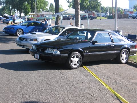 1989 Ford Mustang - Three Ford Mustangs are parked in a lot, including a black 1989 GT model.