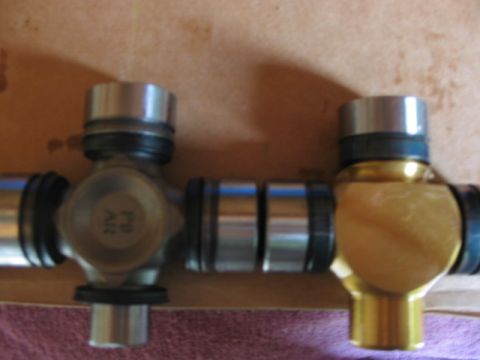 1995 Ford Bronco - Close-up of two universal joints, one silver with part number '21V A18' and one gold, against a cardboard background.