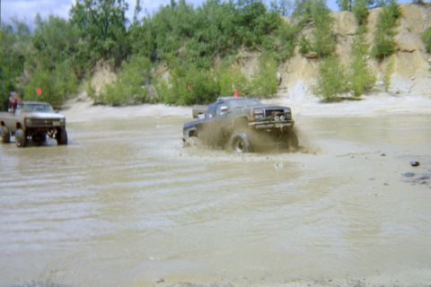 2005 Dodge 1500 - Off-road trucks navigate a muddy terrain, creating splashes as they drive through the water.