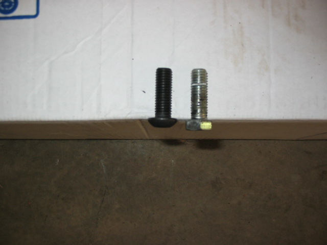 Black button-head bolt next to a shorter zinc-plated bolt on cardboard.