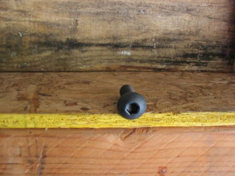 1995 Ford Bronco - A close-up view of a black hex bolt resting on wooden surfaces.