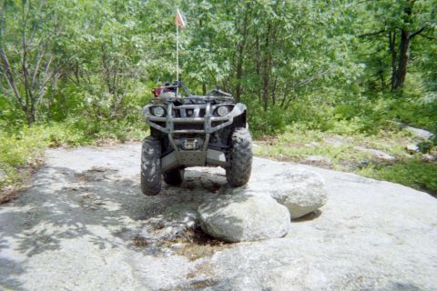 2005 Dodge 1500 - An ATV navigates a rocky trail, its front tires lifted off the ground.
