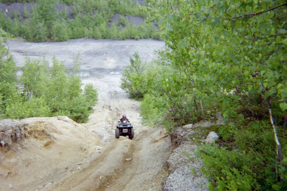 ATV riding down a dirt path in a wooded area