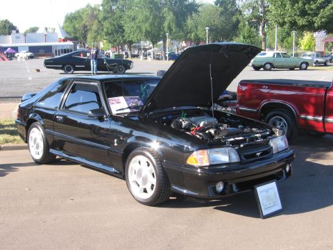 1989 Ford Mustang - A black 1989 Ford Mustang is displayed with its hood open, parked at an outdoor event.