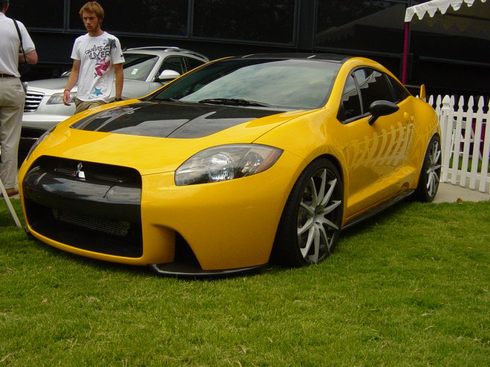 Yellow Mitsubishi Eclipse show car with carbon hood and wide body, 3/4 front on grass