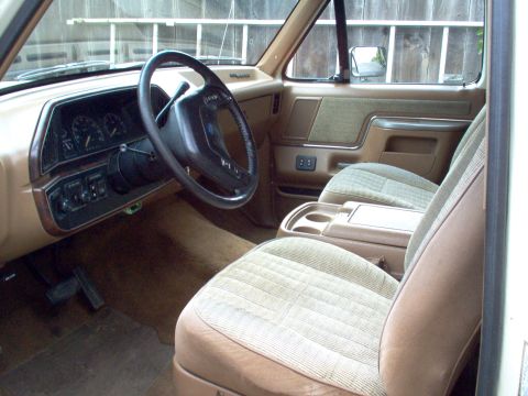 1990 Ford Bronco - The interior of this 1990 Ford Bronco features tan upholstery, a brown dashboard, and a four-spoke steering wheel.