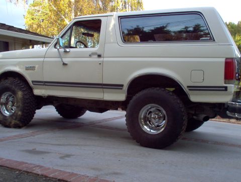 1990 Ford Bronco - Side profile of a lifted white 1990 Ford Bronco with aftermarket wheels and tires.
