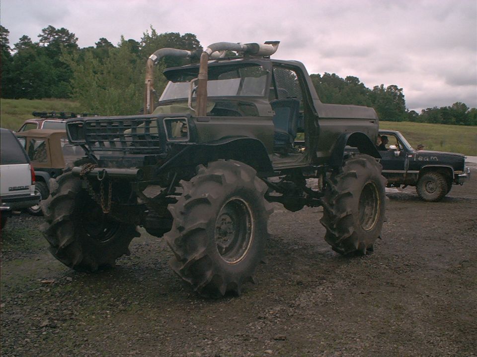 Monster truck with massive mud tires, snorkel exhaust, and open doors