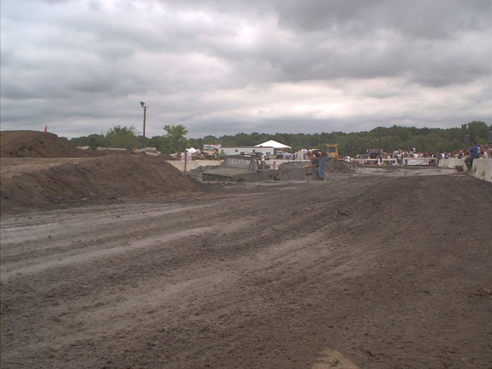 Muddy track with a vehicle stuck in the mud, spectators in the background