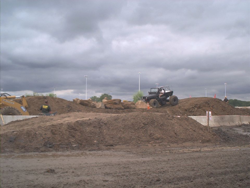 Black Jeep Wrangler climbing a dirt mound on an off-road course