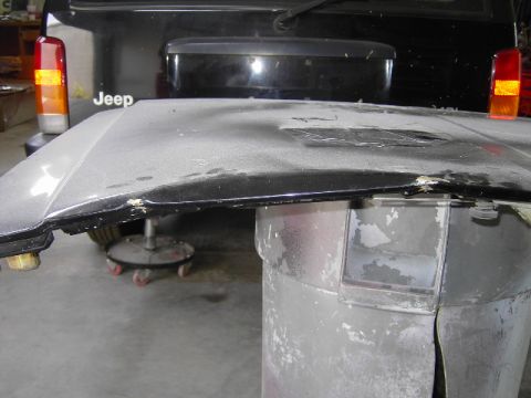 1995 Jeep YJ - A detached Jeep hood rests on a trash can, with another Jeep in the background.