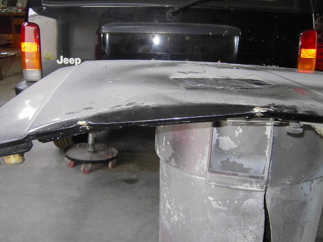 Hood of a Jeep, possibly removed for repair, with another Jeep visible behind it