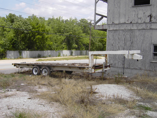 flatbed trailer with gooseneck hitch parked next to a building