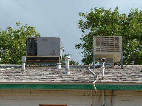 1990 Ford Bronco - Two large HVAC units are visible on a residential roof, with green trees providing a backdrop against a cloudy sky.
