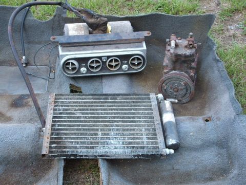 1966 Ford Ranchero - Car air conditioning parts, including a compressor and condenser, are displayed on a carpeted surface.