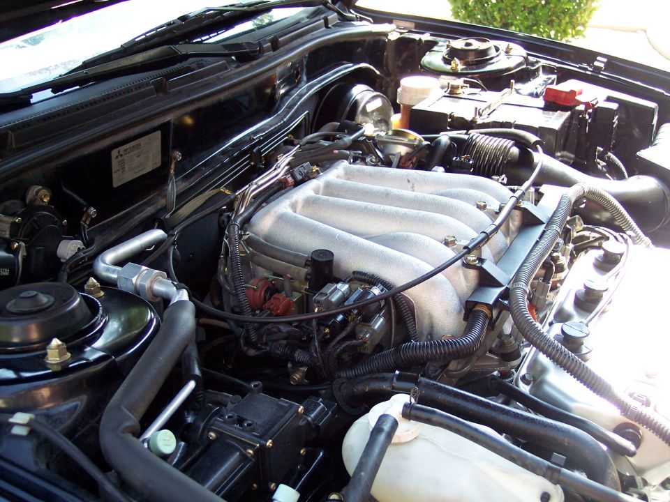 Engine bay with V6 intake manifold, battery, and hoses visible. SuperMotors logo in lower right