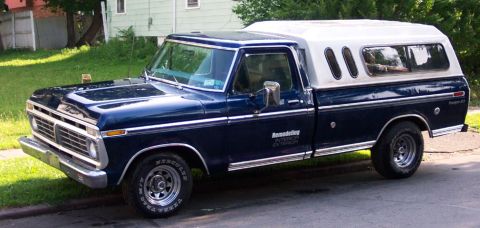 1975 Ford F-150 - This blue 1975 Ford F-150 pickup truck is equipped with a white camper shell and features chrome trim and a prominent grille.