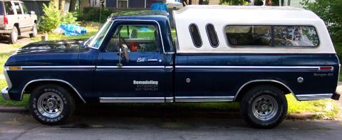 1975 Ford F-150 - Side view of a blue 1975 Ford F-150 pickup truck with a white camper shell, parked on a street.