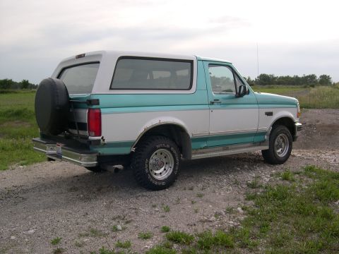 1994 Ford Bronco - Rear view of a two-tone 1994 Ford Bronco with a spare tire on the tailgate.