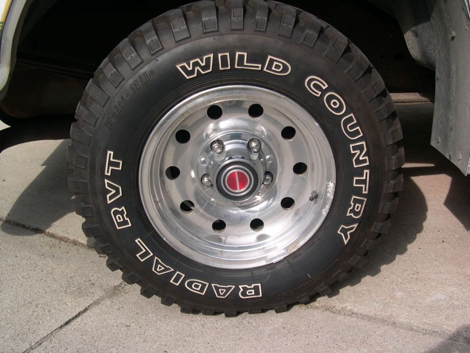 Close-up of a Wild Country Radial RVT tire on a chrome wheel with a red center cap