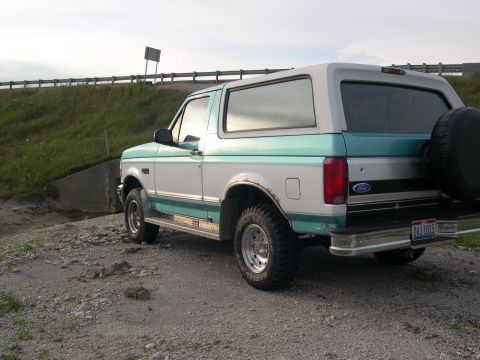 1994 Ford Bronco - This two-tone Ford Bronco is parked on a gravel shoulder next to a grassy embankment.