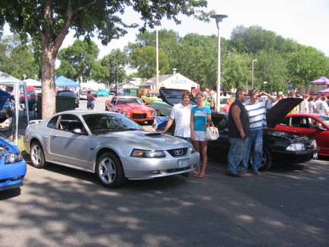 1989 Ford Mustang - A silver Ford Mustang is parked at an outdoor car show with people standing nearby.