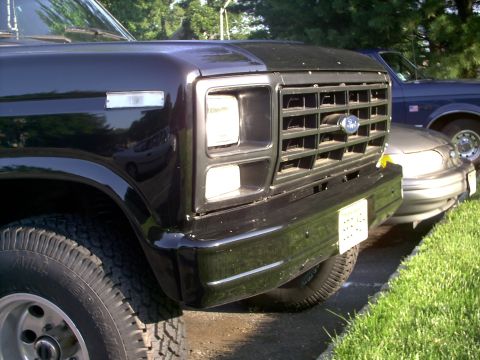 1982 Ford Bronco - Front view of a black Ford truck, likely from the early 1980s, parked next to another vehicle.