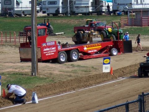 1972 Ford Ranchero - A red truck tows a trailer with a tractor, participating in a truck pull competition.
