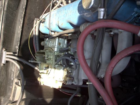 1982 Ford Bronco - Close-up view of an engine bay, focusing on the carburetor and red hoses. Visible text on a hose indicates a date code.